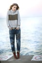 A young blond woman with curly hair on a cement pier next to Lake Michigan.