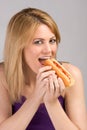 Young blond woman eating hot dog with ketchup Royalty Free Stock Photo