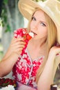 Young blond woman eating strawberries with cream, happy in the garden on a summer sunny day, warm summer tonic image, self-service Royalty Free Stock Photo