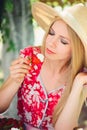 Young blond woman eating strawberries with cream, happy in the garden on a summer sunny day, warm summer tonic image, self-service Royalty Free Stock Photo