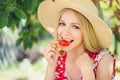 Young blond woman eating strawberries smiling in the garden summer sunny day, warm summer toning image, self care and healthy life Royalty Free Stock Photo