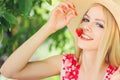 Young blond woman eating strawberries smiling in the garden summer sunny day, warm summer toning image, self care and healthy life Royalty Free Stock Photo