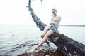 Young blond woman hanging on birch tree at lake shore, summer vacations outdoor lifestyle Royalty Free Stock Photo