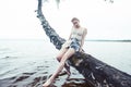 Young blond woman hanging on birch tree at lake shore, summer vacations outdoor lifestyle Royalty Free Stock Photo