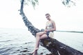 Young blond woman hanging on birch tree at lake shore, summer vacations outdoor lifestyle Royalty Free Stock Photo