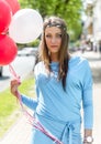 Young blond woman holding colorful balloons in the street. Royalty Free Stock Photo