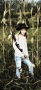 Young blond woman holding a gun and standing in a corn field Royalty Free Stock Photo