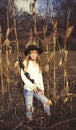 Young blond woman holding a gun and standing in a corn field Royalty Free Stock Photo