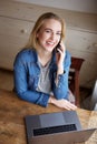 Young blond woman with laptop talking on mobile phone Royalty Free Stock Photo