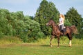 Young blond woman with long hair jockey rider jumping on a bay horse