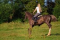 Young blond woman with long hair jockey rider jumping on a bay horse Royalty Free Stock Photo