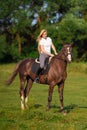 Young blond woman with long hair jockey rider jumping on a bay horse Royalty Free Stock Photo