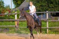 Blond woman with long hair jockey rider on a bay horse, in a paddock on a ranch Royalty Free Stock Photo