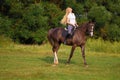 Young blond woman with long hair jockey rider jumping on a bay horse