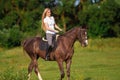 Young blond woman with long hair jockey rider jumping on a bay horse Royalty Free Stock Photo