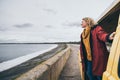 Young blond woman looking out of camper van overlooking the sea Royalty Free Stock Photo