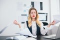 Young blond woman manager with red lipstick works in her modern office, looks relaxed sitting in peaceful yoga position, body