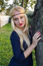 Young blond woman in the park near the tree