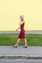 Young blond woman in a red dress walking on the street and talking on the cell phone. Royalty Free Stock Photo