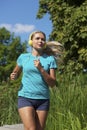 Young blond woman running, listening to music over blue sky Royalty Free Stock Photo