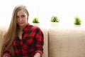 Young blond woman sit on sofa in room