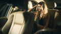 Young blond woman sitting on a backseat of a luxury car Royalty Free Stock Photo