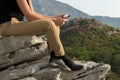 Young blond woman sitting on the edge of the mountain cliff using digital tablet Royalty Free Stock Photo