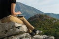 Young blond woman sitting on the edge of the mountain cliff using digital tablet Royalty Free Stock Photo