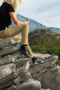 Young blond woman sitting on the edge of the mountain cliff using the smartphone Royalty Free Stock Photo