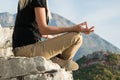 Young blond woman sitting on the edge of the mountain in yoga meditation position cliff against beautiful mountains peak Royalty Free Stock Photo