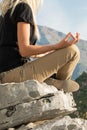 Young blond woman sitting on the edge of the mountain in yoga meditation position cliff against beautiful mountains peak Royalty Free Stock Photo