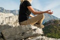 Young blond woman sitting on the edge of the mountain in yoga meditation position cliff against beautiful mountains peak Royalty Free Stock Photo