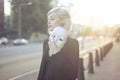 Young blond woman taking off a mask. Pretending to be someone else concept. outdoors on sunset.