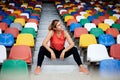 Young blond woman, wearing orange top, black leggings, orange sneakers, sitting on the stairs on stadium tribune, relaxing after