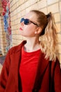 Young blond woman wearing sunglasses and with ponytail by the brick wall Royalty Free Stock Photo
