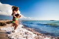 Young blond woman in white bikini and small happy girl entering sea and having fun with sandy beach at background Royalty Free Stock Photo