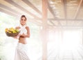 A young blond woman in a white dress holding fruits Royalty Free Stock Photo