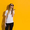 Young Blond Woman In White Shirt And Sunglasses Is Blowing A Kiss