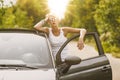 Young blonde attractive woman is ready to enter in her car. She is opening the door and staying behind it Royalty Free Stock Photo