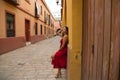 Young, blonde, beautiful woman in a red dress is visiting seville. The woman poses for the camera very elegant and like a model in