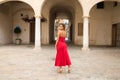 Young, blonde, beautiful woman in a red dress is visiting seville. The woman poses for the camera very elegant and like a model in