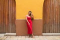 Young, blonde, beautiful woman in a red dress is visiting seville. The woman poses for the camera very elegant and like a model in