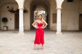 Young, blonde, beautiful woman in a red dress is visiting seville. The woman poses for the camera very elegant and like a model in