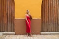 Young, blonde, beautiful woman in a red dress is visiting seville. The woman is posing for the camera very elegant for the photos