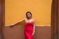 Young, blonde, beautiful woman in a red dress is visiting seville. The woman is posing for the camera very elegant for the photos