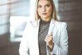 Young blonde business woman or female student standing straight and posing at camera in sunny office Royalty Free Stock Photo