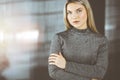 Young blonde business woman or female student standing straight and posing at camera in sunny office Royalty Free Stock Photo