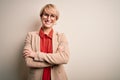 Young blonde business woman with short hair wearing glasses and elegant jacket happy face smiling with crossed arms looking at the Royalty Free Stock Photo