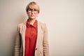 Young blonde business woman with short hair wearing glasses and elegant jacket with serious expression on face Royalty Free Stock Photo