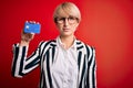 Young blonde business woman with short hair wearing glasses holding credit card with a confident expression on smart face thinking Royalty Free Stock Photo